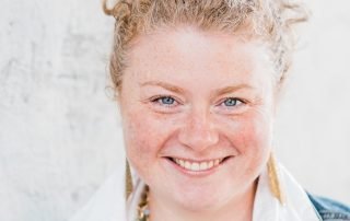 Portrait photo of a smiling woman with wavy hair in a denim jacket