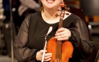 Portrait photo of a musician smiling with viola in concert attire