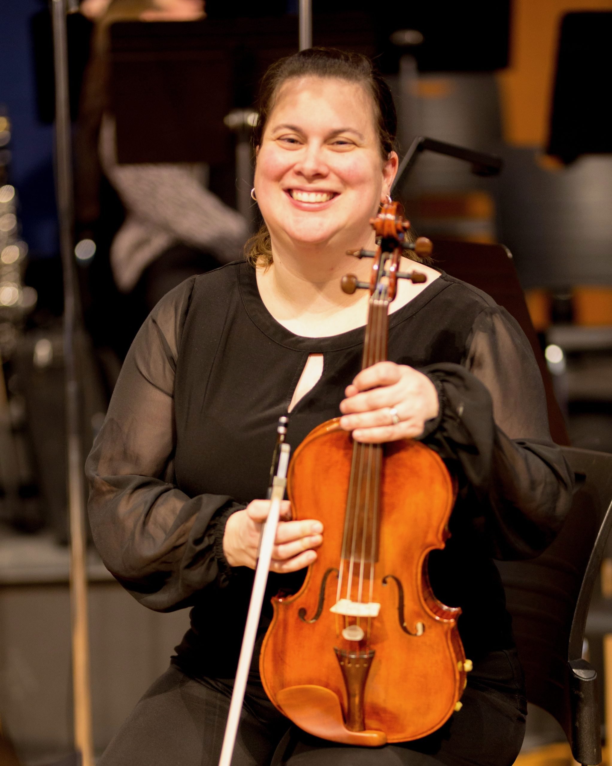 Portrait photo of a musician smiling with viola in concert attire